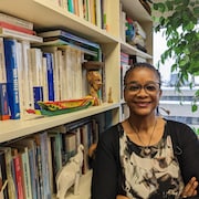 Marie Fall, professeure de géographie et coopération internationale à l'UQAC, prise en photo dans son bureau. Elle est près d'une bibliothèque remplie de livres.
